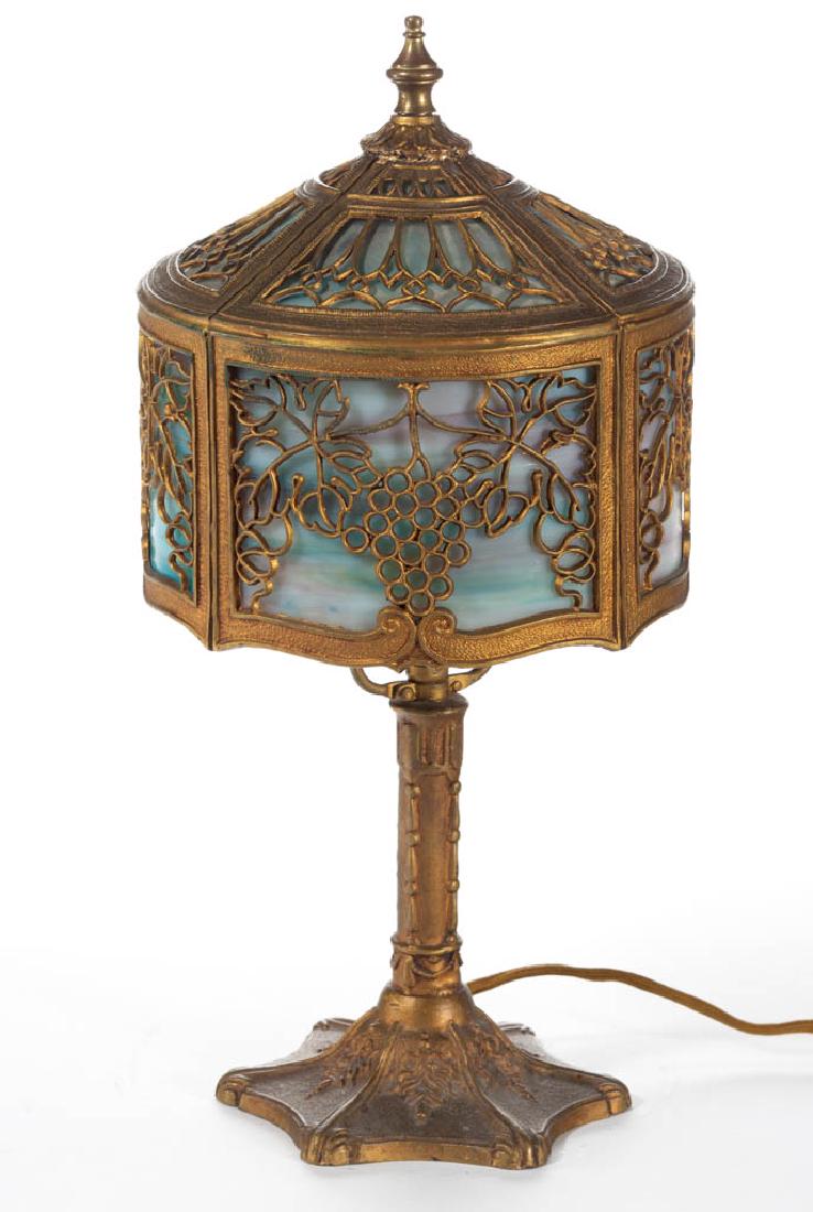 METAL-OVERLAY SLAG GLASS BOUDOIR LAMP: METAL-OVERLAY SLAG GLASS BOUDOIR LAMP, polychrome glass panels, concave hexagonal base with embossed floral design with a cylindrical stem with pillars, period socket and harp. Topped with a tapered c
