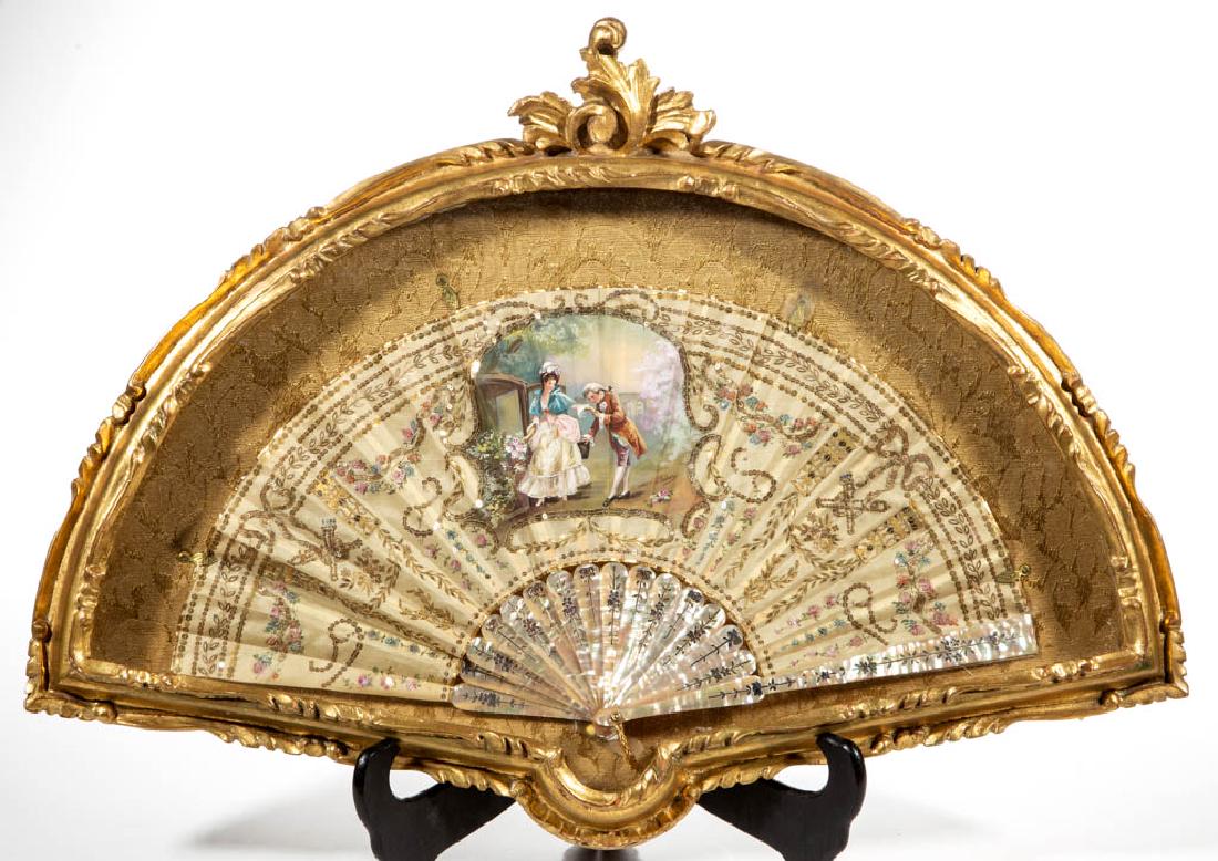 FRENCH SILK AND MOTHER-OF-PEARL LADY'S HAND FAN: FRENCH SILK AND MOTHER-OF-PEARL LADY'S HAND FAN, central hand-painted vignette depicting a young couple in Colonial garb, signed "J. Kahenn" for Jeanne Kahenn, surrounded by intricate metallic-thread 