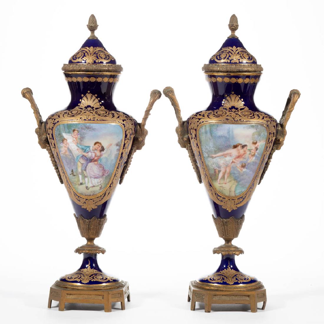 PAIR OF FRENCH SEVRES PORCELAIN ORMOLU-MOUNTED COVERED: PAIR OF FRENCH SEVRES PORCELAIN ORMOLU-MOUNTED COVERED URNS, both sides having hand-painted panels with scenes depicting amorous couples with cherubs and buildings beside water, each signed "A. Vigier
