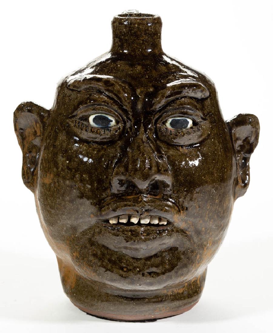 SIGNED "LANIER MEADERS" (1917-1998) GEORGIA STONEWARE: SIGNED "LANIER MEADERS" (1917-1998) GEORGIA STONEWARE FACE JUG, mottled green alkaline glaze, inset ceramic eyes, applied ears, nose, eyebrows, and white clay teeth. Incised "Lanier / Meaders" on base