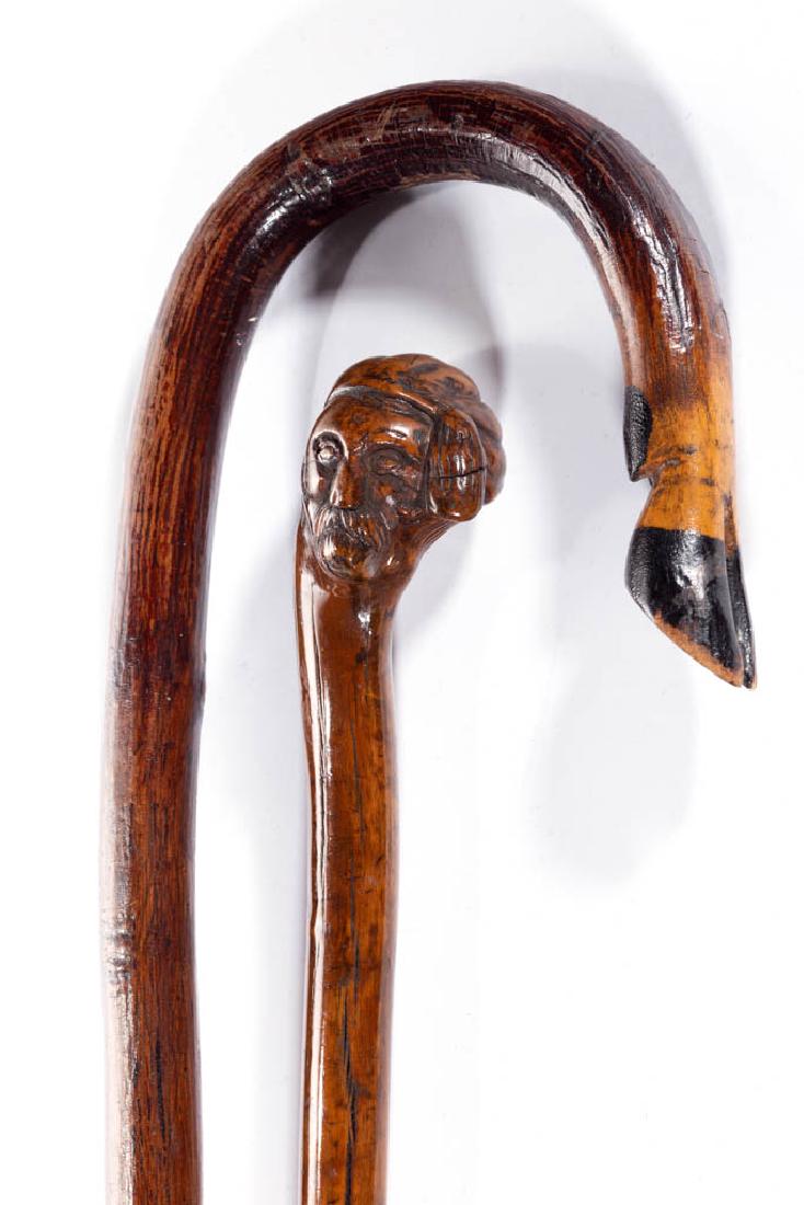 FOLK ART CARVED CANES / WALKING STICKS, LOT OF TWO: FOLK ART CARVED CANES / WALKING STICKS, LOT OF TWO, comprising one with deer hoof for handle, and another, possibly a "shillelagh", with a carved mustached man as a handle. Original varnished-and-pain