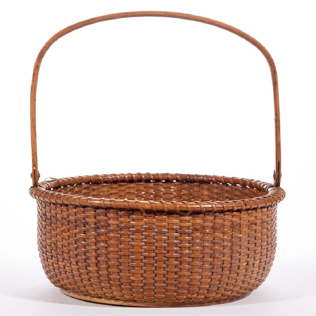NANTUCKET LIGHTSHIP BASKET: NANTUCKET LIGHTSHIP BASKET, low circular stave-type form of large size with wrapped rim, high arched swing handle pinned to a cut-copper rim attachment, and turned wooden bottom, old pencil signature 