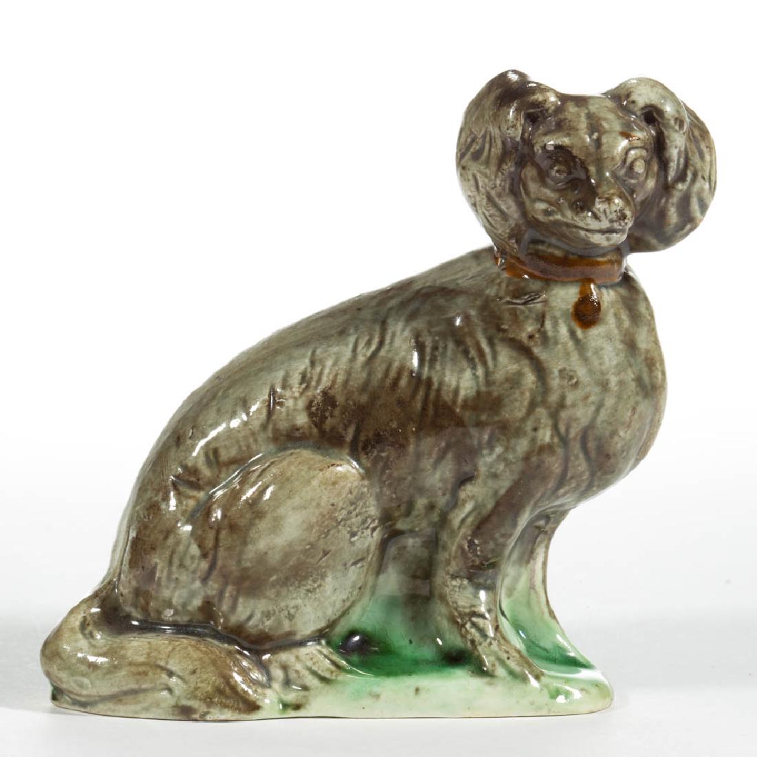 ENGLISH STAFFORDSHIRE PEARLWARE CERAMIC DOG / SPANIEL: ENGLISH STAFFORDSHIRE PEARLWARE CERAMIC DOG / SPANIEL FIGURE, sitting on a green oval base, wearing a brown collar, with mottled green and brown glaze decoration, decorated in the round, open-bottomed