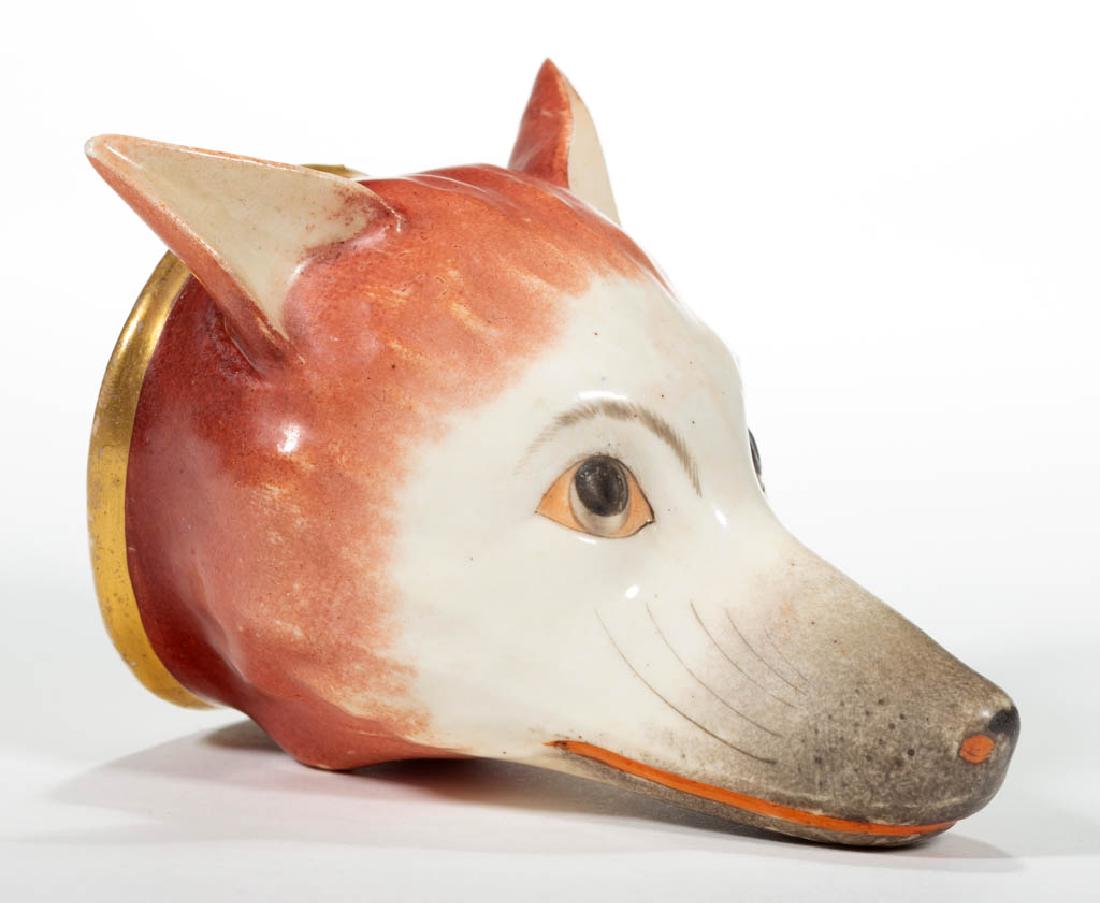 ENGLISH STAFFORDSHIRE CERAMIC FOX STIRRUP CUP: ENGLISH STAFFORDSHIRE CERAMIC FOX STIRRUP CUP, having raised ears featuring realistic polychrome hand-painted decoration with a gilt collar. Circa 1830. 3 3/4" HOA, 2 1/2" D.Having professional restor