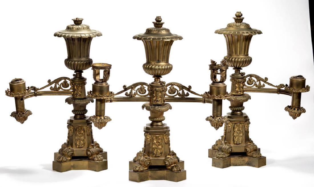 J. & I. COX CAST-BRONZE THREE-PIECE ARGAND LAMP: J. & I. COX CAST-BRONZE THREE-PIECE ARGAND LAMP GARNITURE, comprising one double-arm and two single-arm examples, each having ribbed vertical fonts with horizontal arms with cast-scrolling decoration,