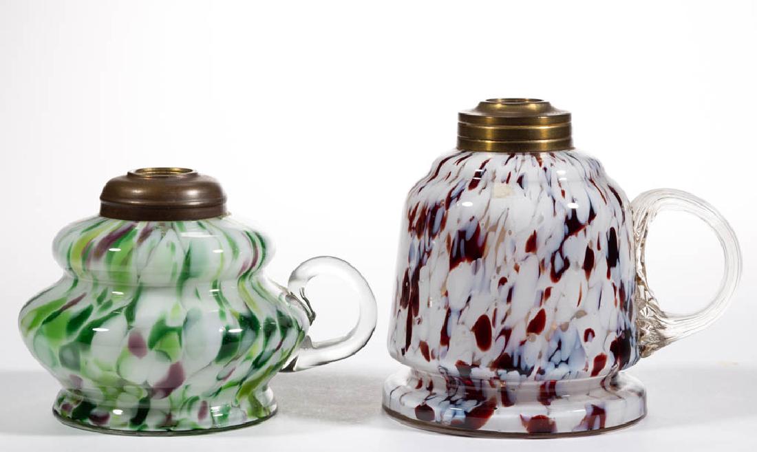 ASSORTED SPATTER GLASS KEROSENE FINGER LAMPS, LOT OF: ASSORTED SPATTER GLASS KEROSENE FINGER LAMPS, LOT OF TWO, comprising a bell-form example with ringed foot, opal and burgundy flakes; and a compressed bulging form, green, opal and lavender flakes, eac