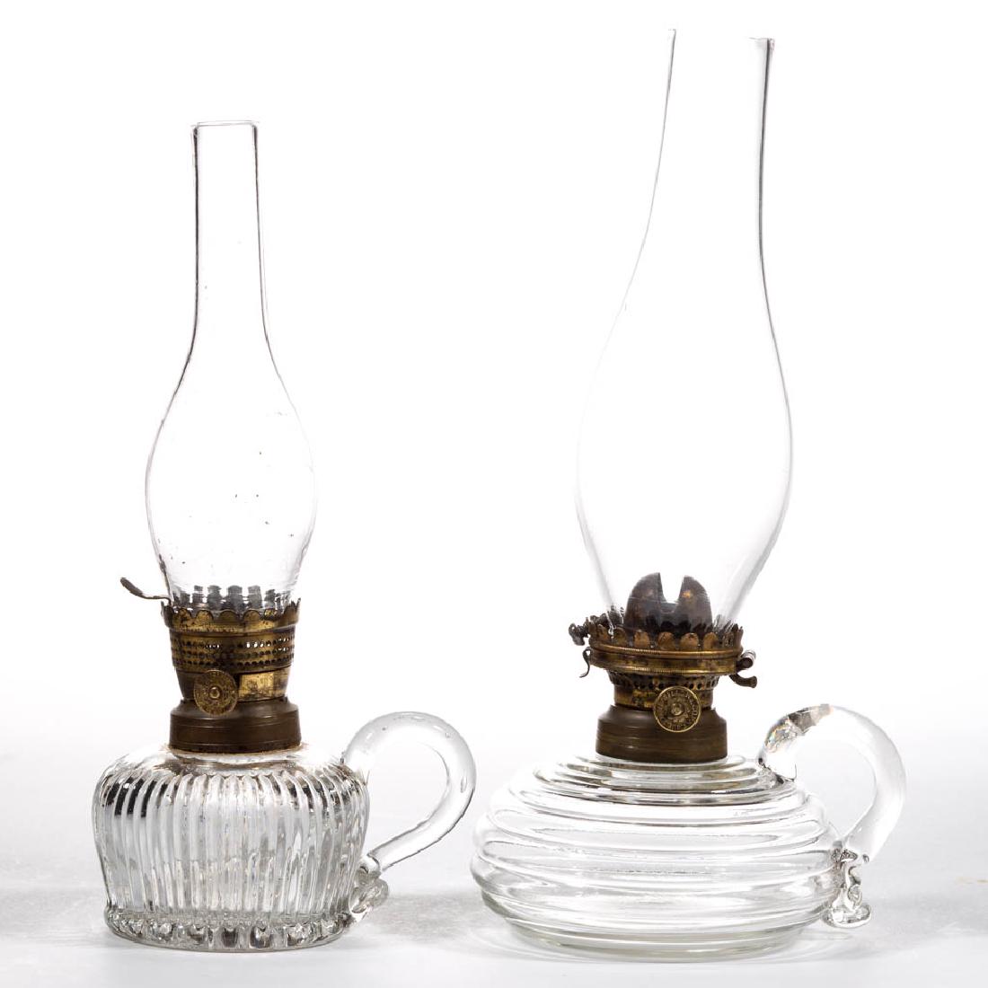 ASSORTED PRESSED GLASS MINIATURE FINGER LAMPS, LOT OF: ASSORTED PRESSED GLASS MINIATURE FINGER LAMPS, LOT OF TWO, colorless, comprising a compressed beehive and a prism example. Beehive fitted with an "E. MILLER" No. 0 lip burner and colorless lip chimney
