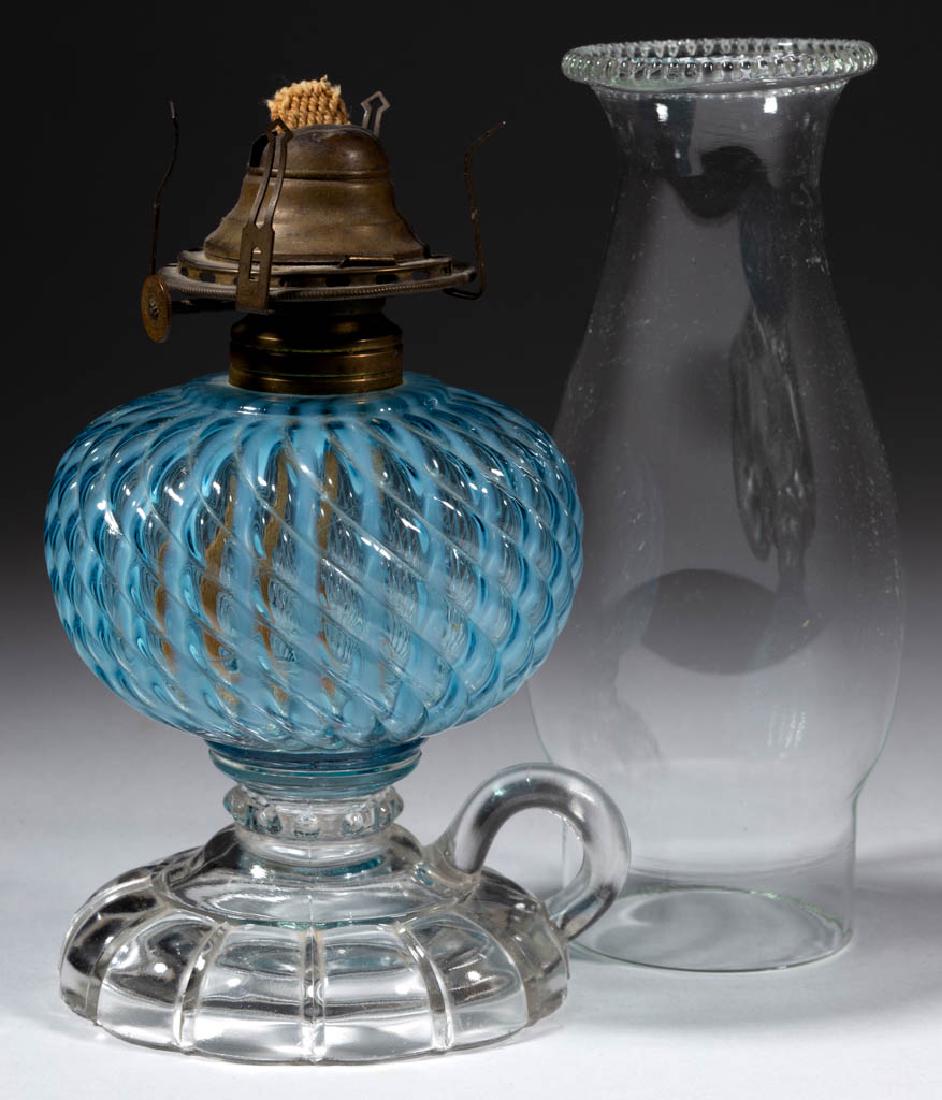 SHELDON SWIRL KEROSENE FOOTED FINGER LAMP: SHELDON SWIRL KEROSENE FOOTED FINGER LAMP, blue opalescent Reverse Swirl font, colorless base, No. 1 Taplin-Brown collar. Fitted with a period No. 1 "RAYO/QUEEN-ANNE" slip burner and colorless slip ch