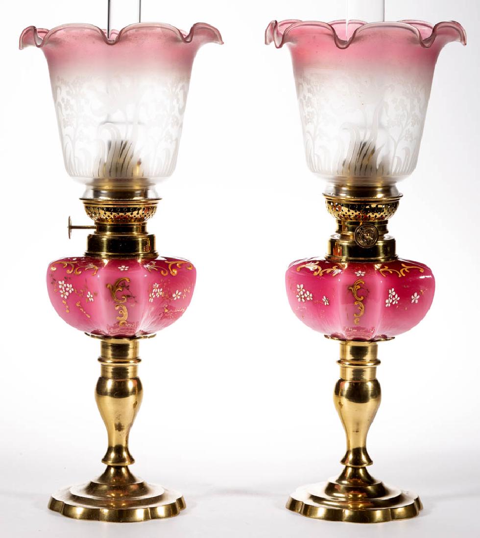 VICTORIAN DECORATED PAIR OF KEROSENE PEG LAMPS,: VICTORIAN DECORATED PAIR OF KEROSENE PEG LAMPS,, cased dark to light rose with stylized enamel and gilt decoration, hexagonal-form fonts with concave sides, period No. 2 collars, brass candlesticks wi