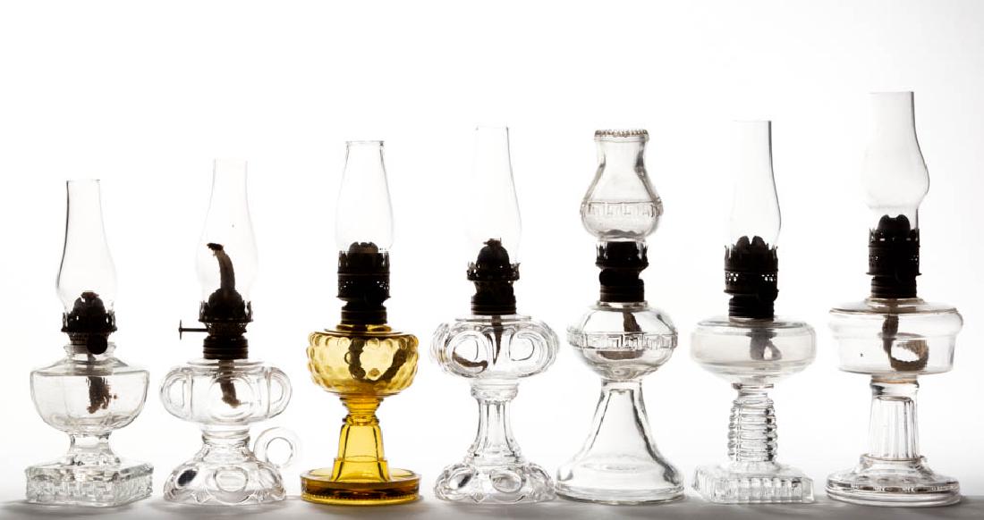 ASSORTED PRESSED PATTERN MINIATURE STAND AND FOOTED: ASSORTED PRESSED PATTERN MINIATURE STAND AND FOOTED FINGER LAMPS, LOT OF SEVEN, amber and colorless, including two Daisy/Smith I, fig. 112 examples; two Greek Key examples; a Hobbs No. 338/Optic Smith