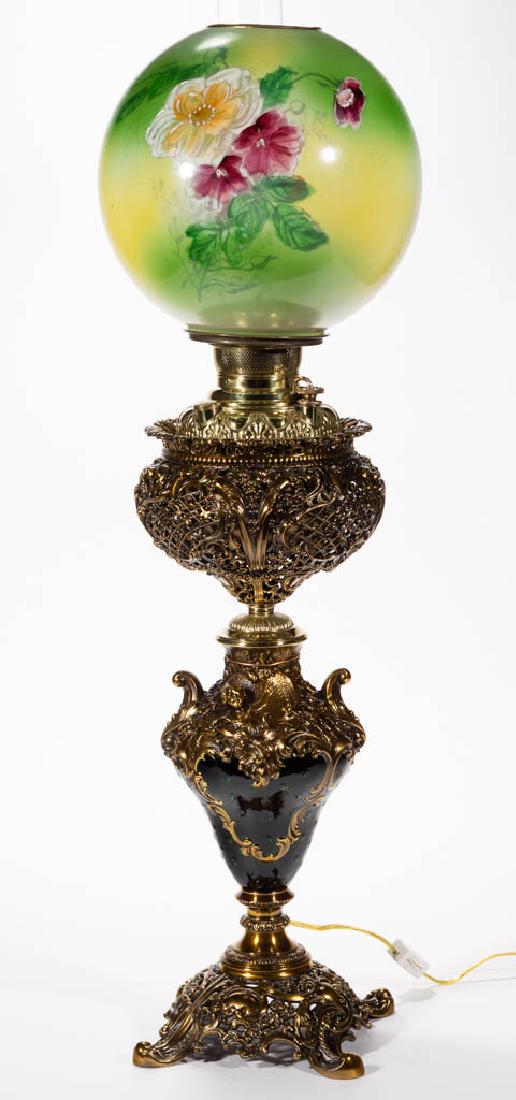 E. MILLER CAST-BRASS AND ENAMEL-DECORATED KEROSENE: E. MILLER CAST-BRASS AND ENAMEL-DECORATED KEROSENE BANQUET LAMP, opaque white ball shade with green ground and polychrome-enamel floral decoration, openwork gothic floral and scrolling font vase, "THE