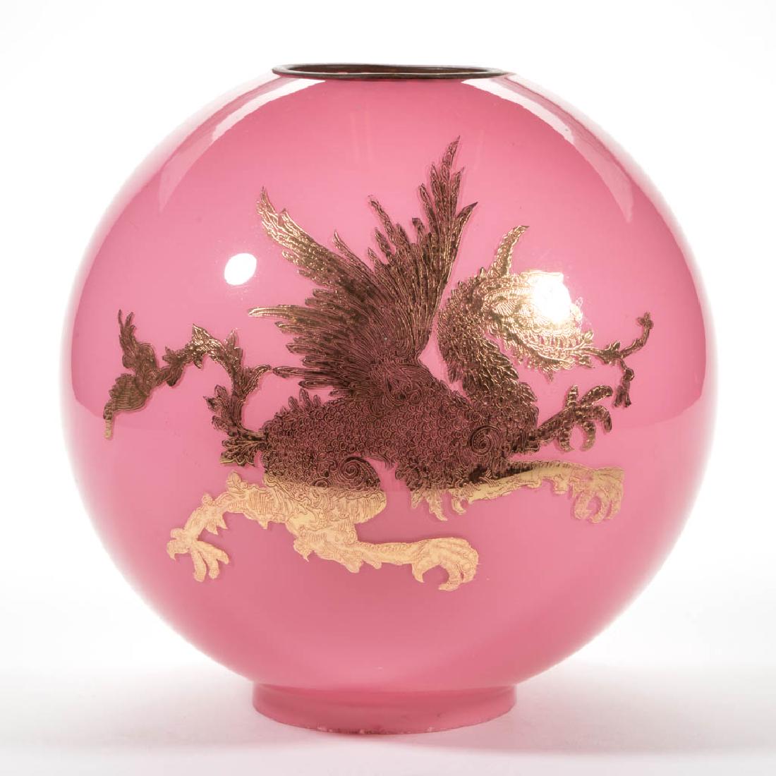 VICTORIAN SINGLE-DRAGON GILT-STENCILED CASED GLASS BALL: VICTORIAN SINGLE-DRAGON GILT-STENCILED CASED GLASS BALL SHADE, opal cased pink, a dragon to each face, loose brass cap ring. Maker unverified. Late 19th/early 20th century. 9 1/2" H, 4" D fitter. Exce