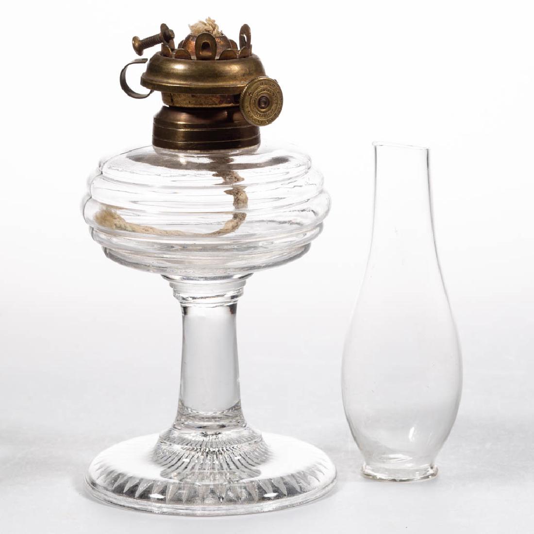 HOLMES, BOOTH & HAYDENS "NE PLUS ULTRA" KEROSENE LIP: HOLMES, BOOTH & HAYDENS "NE PLUS ULTRA" KEROSENE LIP BURNER, brass, thumbwheel marked "HOLMES BOOTH. & HAYDENS. / PATENT. JAN. 24. 1860.", round wick. period colorless lip chimney. Fitted on a colorle