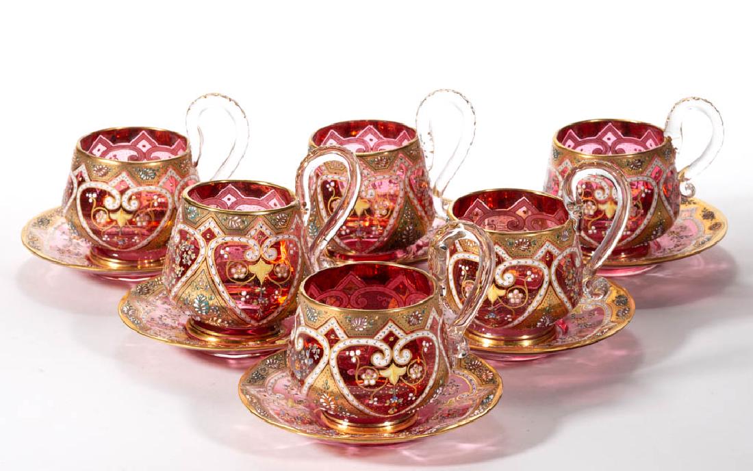 MOSER ATTRIBUTED ENAMEL-DECORATED CUP AND SAUCER SETS,: MOSER ATTRIBUTED ENAMEL-DECORATED CUP AND SAUCER SETS, LOT OF SIX, cranberry with matching polychrome-enamel decoration, each with polished pontil mark. Twelve (12) pieces total. Bohemia, now Czech Re