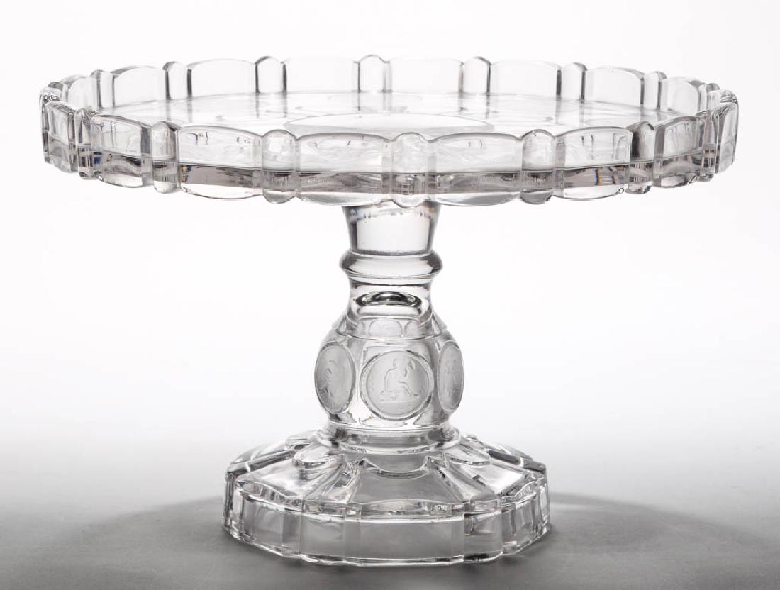 U. S. COIN / SILVER AGE (OMN) CAKE STAND / SALVER: U. S. COIN / SILVER AGE (OMN) CAKE STAND / SALVER, colorless and frosted, plate with shaped rim and nine dollar coins, raised on a stem with six quarter-dollar coins and shaped foot. Central Glass Co.