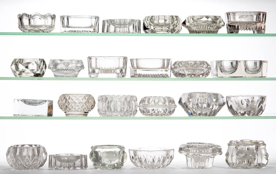 ASSORTED PRESSED MASTER OPEN SALTS, LOT OF 24: ASSORTED PRESSED MASTER OPEN SALTS, LOT OF 24, colorless, some lead glass, flat forms, one double example. Second half 19th/early 20th century. 1 1/4" to 2 1/4" H. Some undamaged, remainder average wi
