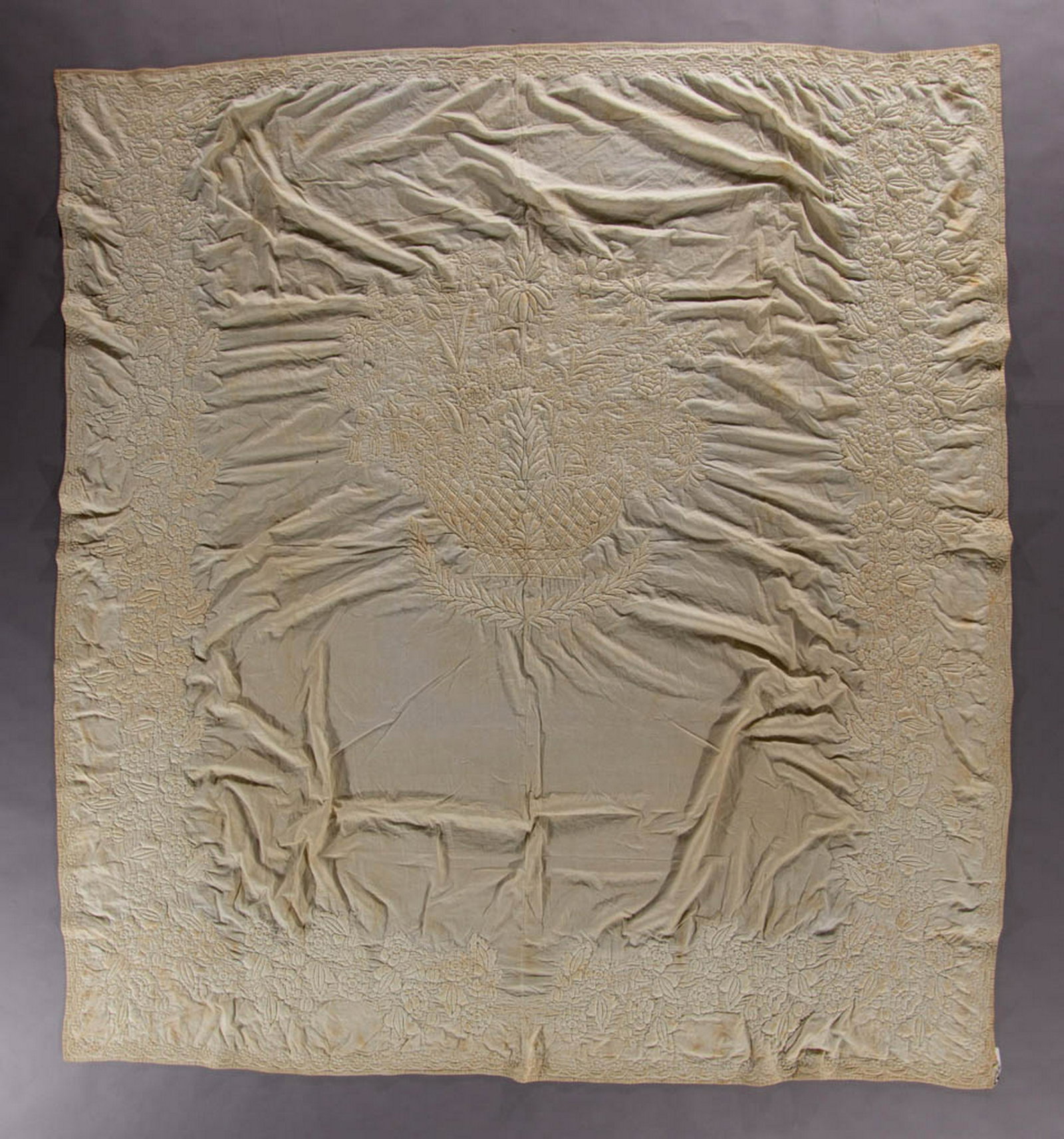 AMERICAN TRAPUNTO WHITEWORK COUNTERPANE: AMERICAN TRAPUNTO WHITEWORK COUNTERPANE, hand-stitched, two joined panels having intricate stuffed/trapunto designs with tight outline quilting, featuring a central basket of flowers, a floral garland