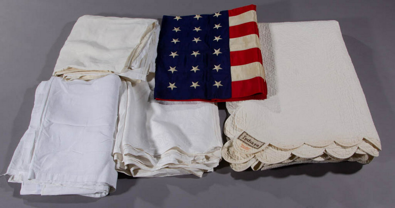 ASSORTED TEXTILE ARTICLES, LOT OF FIVE: ASSORTED TEXTILE ARTICLES, LOT OF FIVE, comprising a silk 48-star American flag with machine stitching, a damask tablecloth measuring 102 1/2" x 88 1/2", two modern linen flat sheets, and a hand-stitc