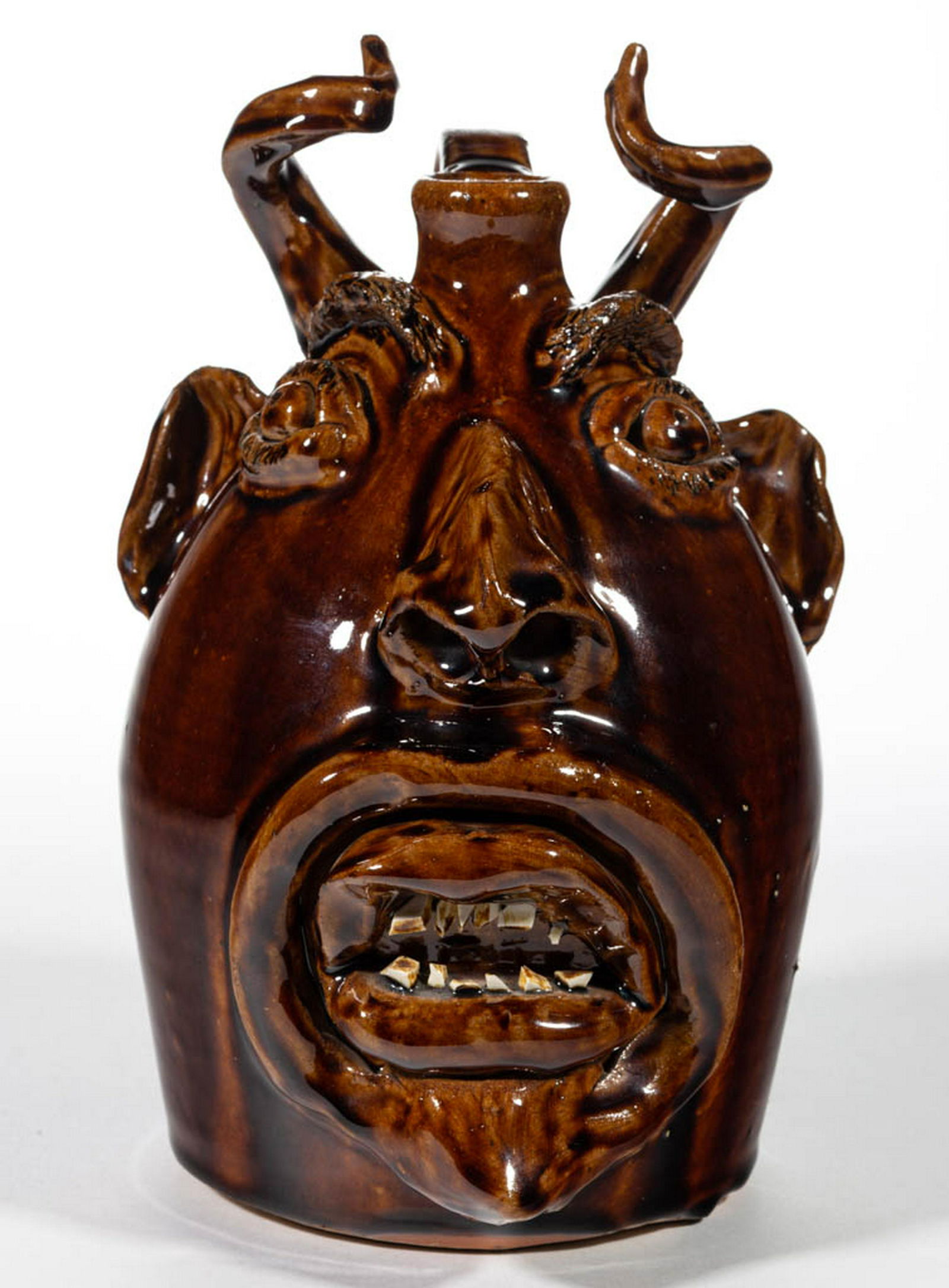 SIGNED "BROWN'S POTTERY / ARDEN, NC", NORTH CAROLINA: SIGNED "BROWN'S POTTERY / ARDEN, NC", NORTH CAROLINA STONEWARE FACE JUG, brown-glazed, expressive form featuring curled horns, bushy eyebrows and incised eye lashes, clay eyes, protruding nose with pi