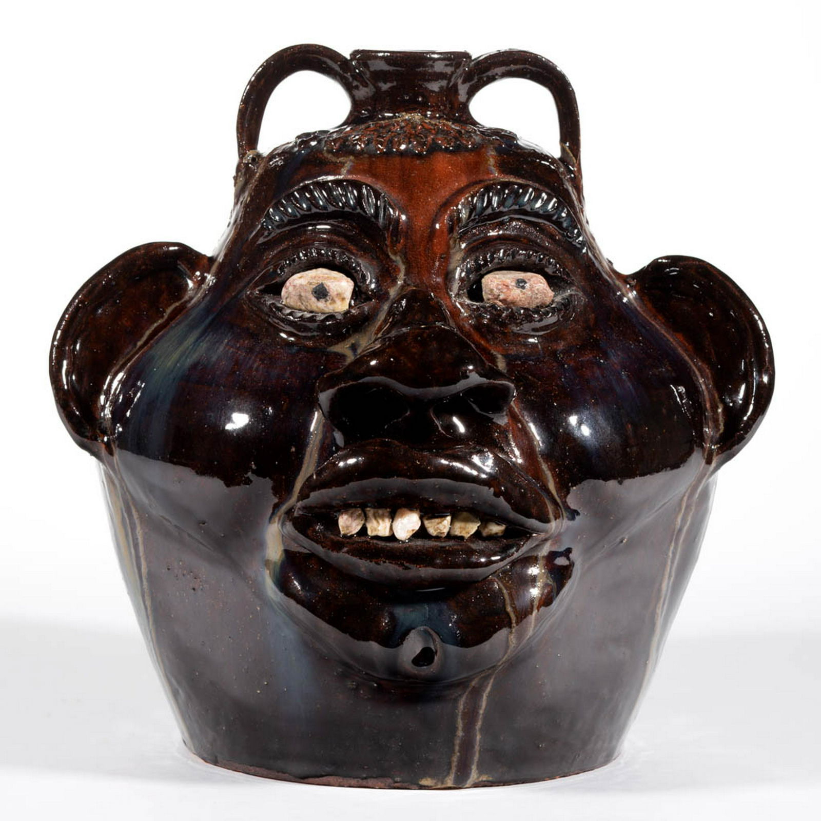 SIGNED "ALBERT HODGE", VALE, NORTH CAROLINA EARTHENWARE: SIGNED "ALBERT HODGE", VALE, NORTH CAROLINA EARTHENWARE / REDWARE FACE JUG, alkaline-glazed, having molded hair to front, inset white gravel/stone eyes with black painted pupils, applied ears, promine