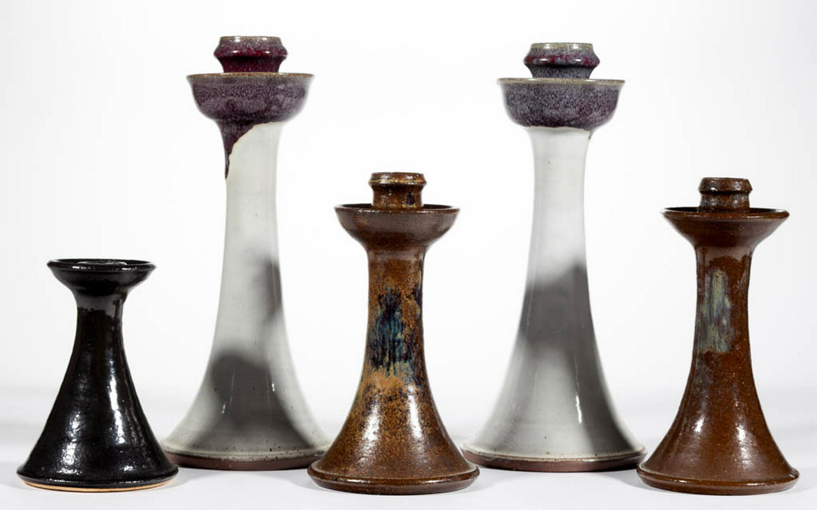 NORTH CAROLINA EARTHENWARE / STONEWARE CANDLESTICKS,: NORTH CAROLINA EARTHENWARE / STONEWARE CANDLESTICKS, LOT OF FIVE, comprising a matching pair having purple/blue glaze dripped over a light gray ground, signed "Vernon Owens" and stamped "JUGTOWN / WAR