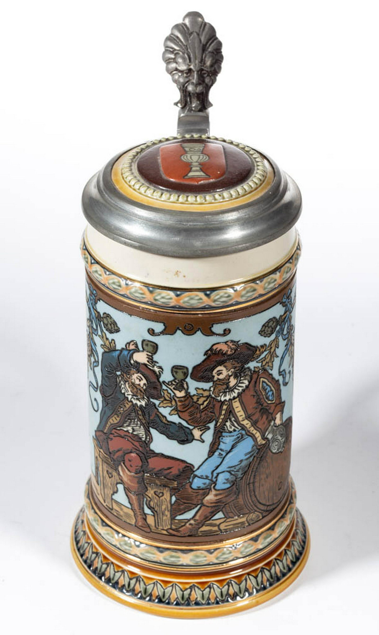GERMAN METTLACH CAVALIERS DRINKING CERAMIC STEIN: GERMAN METTLACH CAVALIERS DRINKING CERAMIC STEIN, mold number 1932, having etched sides with scene of two men in cavalier-type clothing drinking beer, flanked by two banners reading "Ein Glas beim Fre