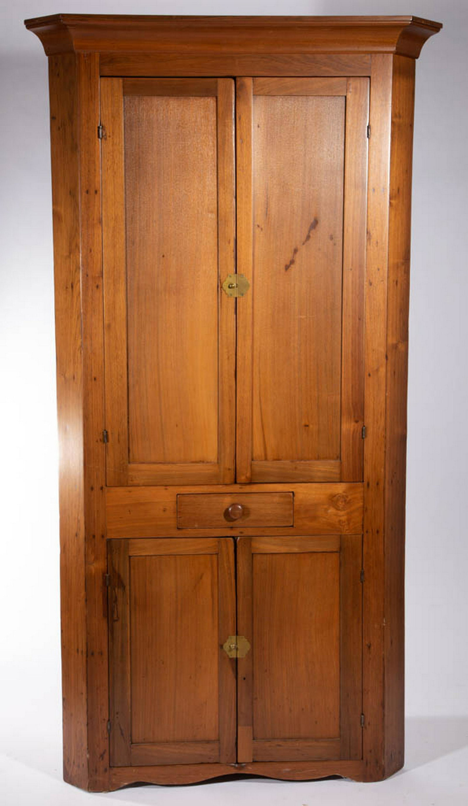 AMERICAN COUNTRY WALNUT CORNER CUPBOARD: AMERICAN COUNTRY WALNUT CORNER CUPBOARD, one-piece construction, cove-molded cornice, fielded-panel doors, single drawer at waist. Refinished surface. 19th century. 84" H, 25" corner. Cornice replaced