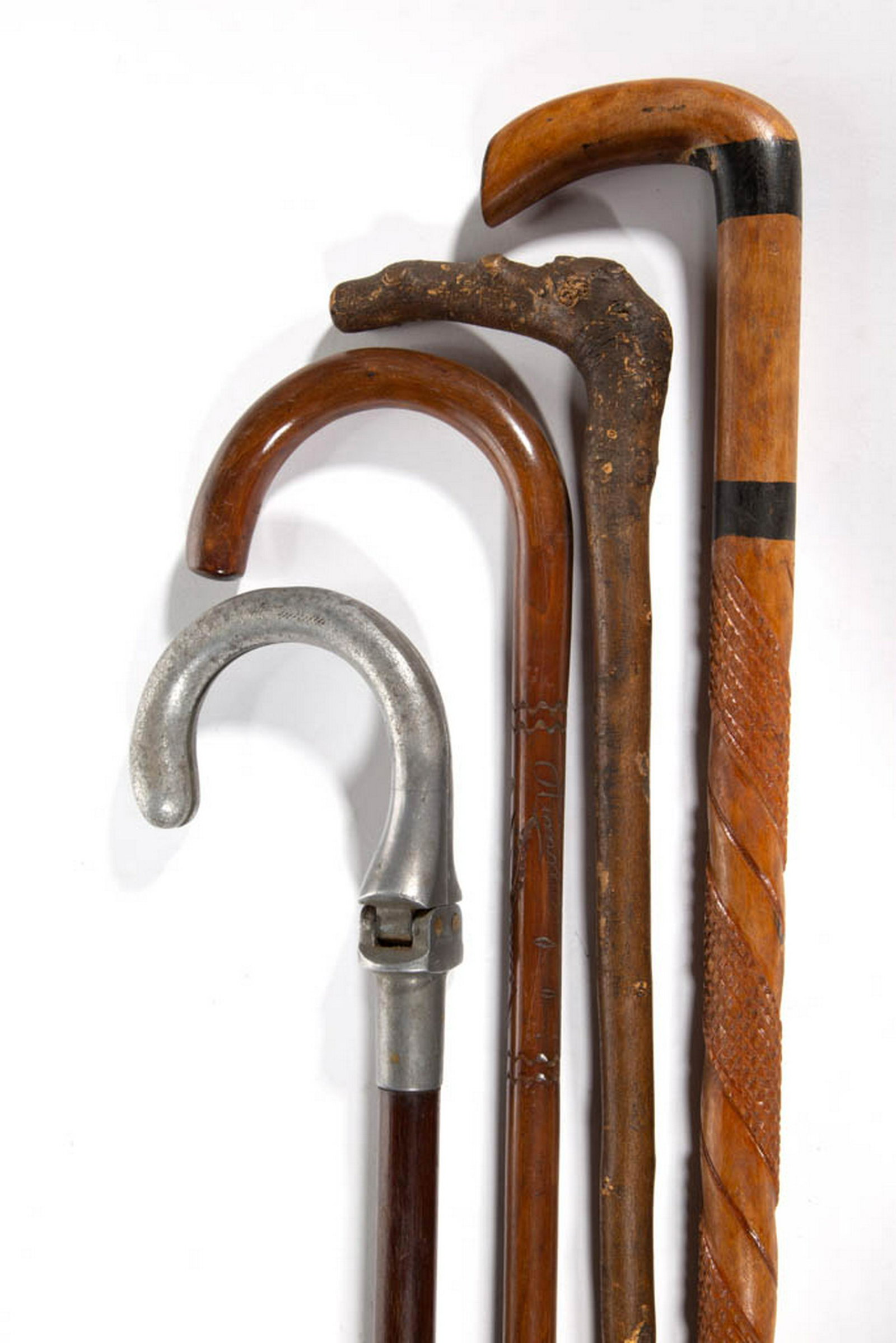 ASSORTED WOODEN CANES / WALKING STICKS, LOT OF FOUR: ASSORTED WOODEN CANES / WALKING STICKS, LOT OF FOUR, including one signed "Himmelbjerget", and "THE "SCOUT" SEAT" made by "HOWELL / LONDON". First half 20th century. 34 1/2" to 35 3/4" L. Very good ov