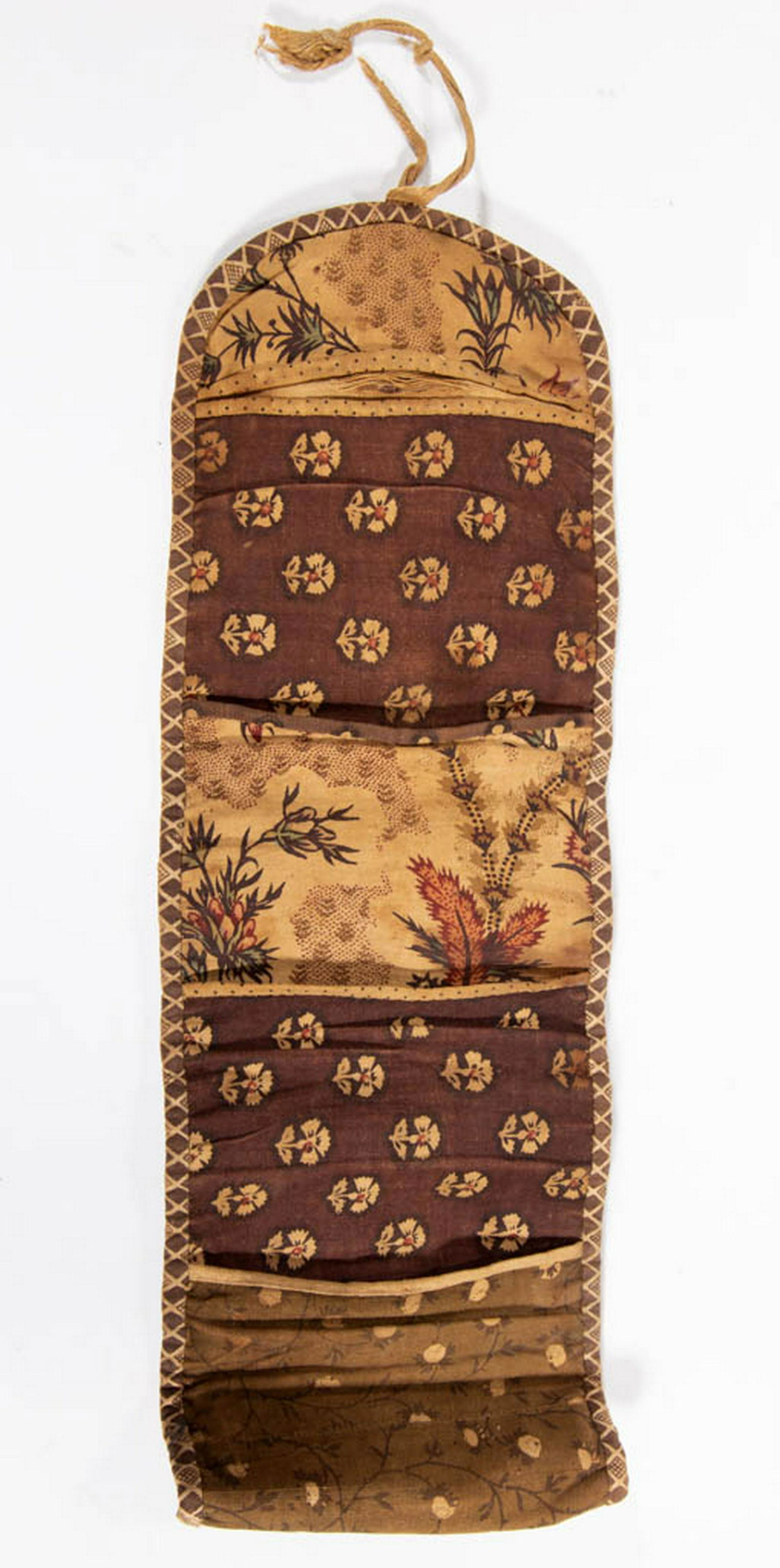 SEWING ROLL-UP / HOUSEWIFE: SEWING ROLL-UP / HOUSEWIFE, hand-stitched, various printed fabrics having four lined interior pockets, applied binding along edges, rolls up with a ribbon tie closure. First half 19th century. 5" W, 1