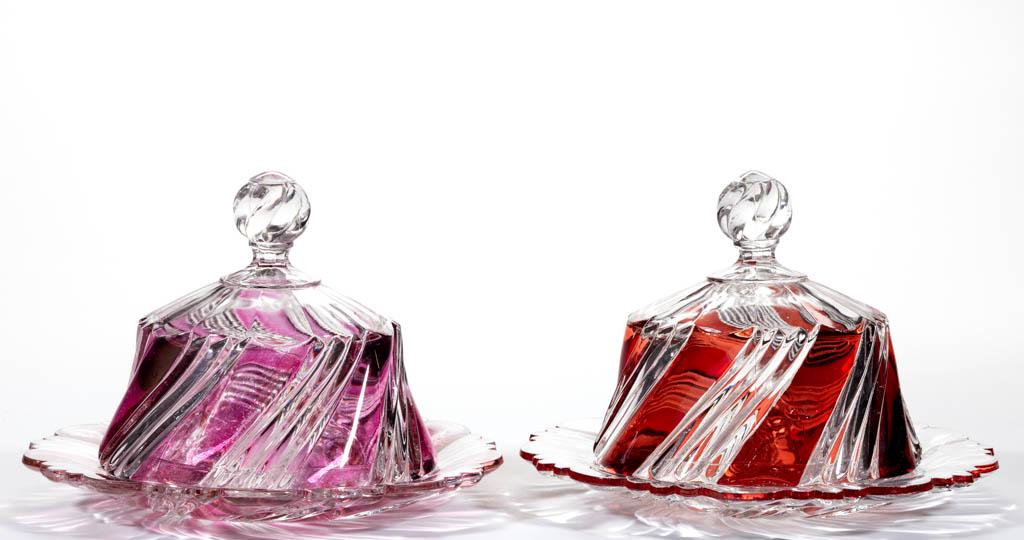 DUNCAN NO. 51 / TWO-PLY SWIRL - STAINED COVERED BUTTER: DUNCAN NO. 51 / TWO-PLY SWIRL - STAINED COVERED BUTTER DISHES, LOT OF TWO, colorless, comprising a ruby-stained and a maiden's blush-stained example. Duncan & Miller Glass Co. Pattern introduced in 19
