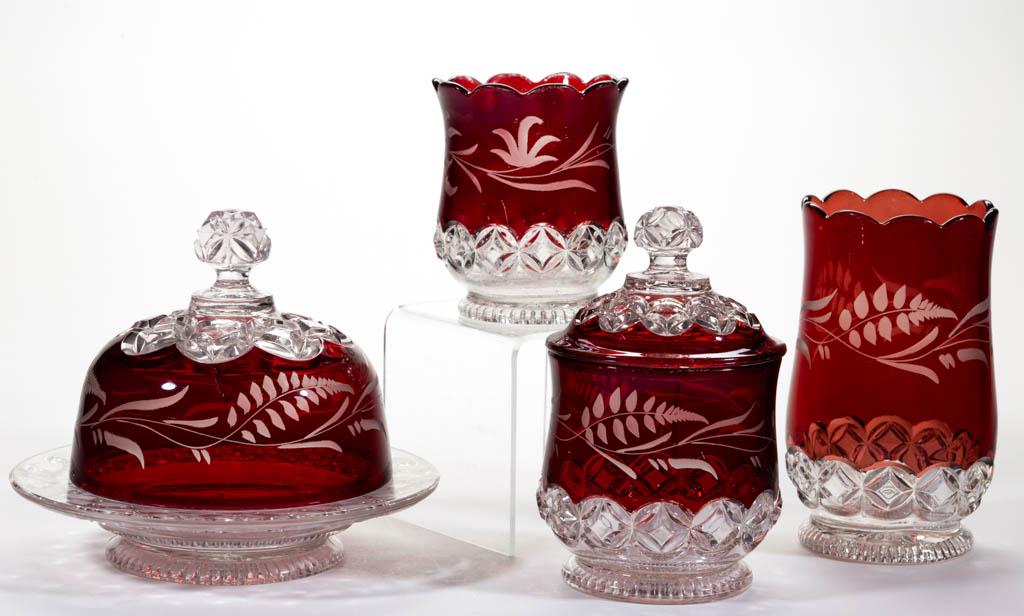 HERO / RUBY ROSETTE - RUBY-STAINED TABLE ARTICLES, LOT: HERO / RUBY ROSETTE - RUBY-STAINED TABLE ARTICLES, LOT OF FOUR, colorless with matching engraved decoration, comprising a covered butter dish, covered sugar bowl, spooner, and celery vase. Elson Glass