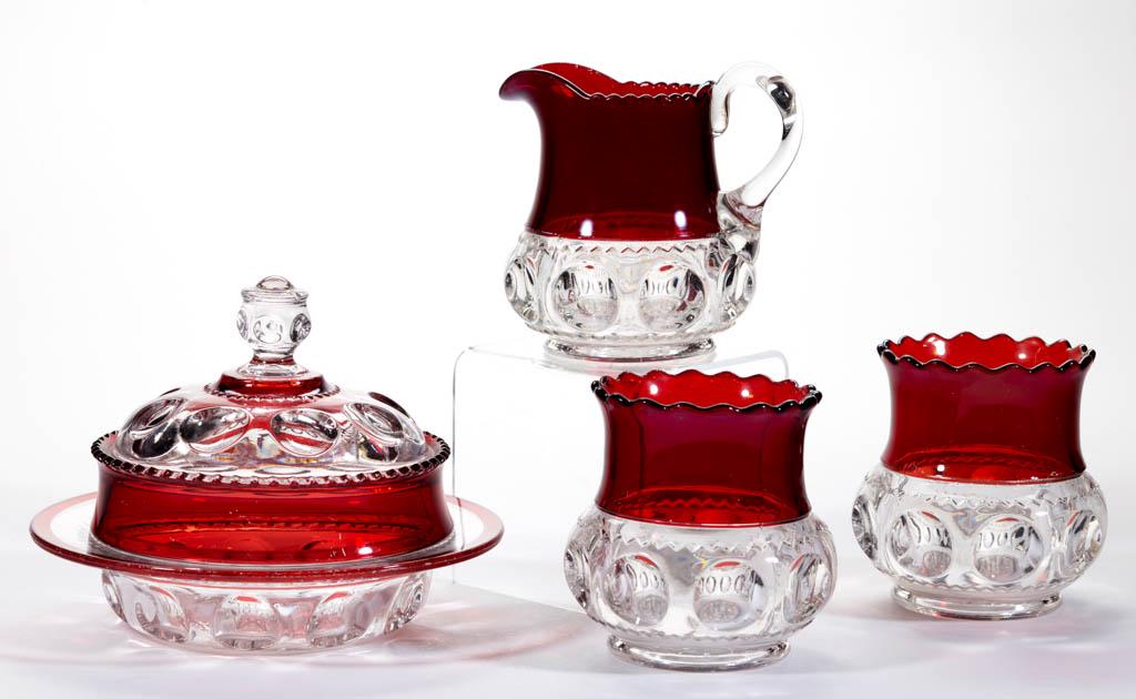 KING'S CROWN / EXCELSIOR (OMN) - RUBY-STAINED TABLE: KING'S CROWN / EXCELSIOR (OMN) - RUBY-STAINED TABLE ARTICLES, LOT OF FOUR, colorless, comprising a covered butter dish, a creamer, and two spooners. Adams & Co. Pattern introduced in 1891. 4 1/4" to 5