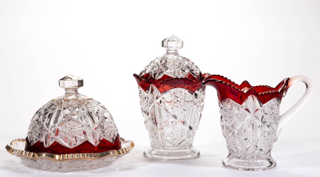 TOLTEC - RUBY-STAINED TABLE ARTICLES, LOT OF THREE: TOLTEC - RUBY-STAINED TABLE ARTICLES, LOT OF THREE, colorless with gilt decoration, comprising a covered butter dish, covered sugar bowl, and creamer. McKee-Jeannette Glass Works. Pattern introduced i