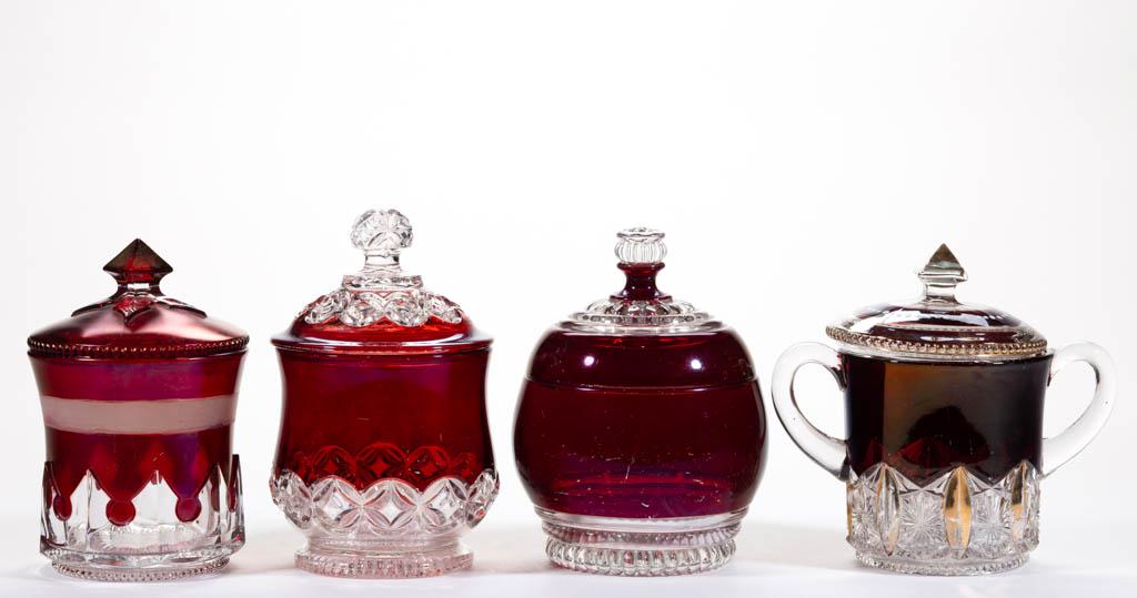 ASSORTED EAPG - RUBY-STAINED COVERED SUGAR BOWLS, LOT: ASSORTED EAPG - RUBY-STAINED COVERED SUGAR BOWLS, LOT OF FOUR, colorless, including a Hero, a McKee's Gothic, and a Beaded Lobe. Various makers. Fourth quarter 19th/first quarter 20th century. 6" to 6