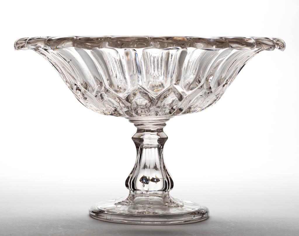 UNIDENTIFIED FLINT EAPG OPEN COMPOTE: UNIDENTIFIED FLINT EAPG OPEN COMPOTE, colorless lead glass, bowl featuring a row of elongated ovals above a band of thumbprints, and slightly rolled-over rim with 22 wide scallops, raised on a standar