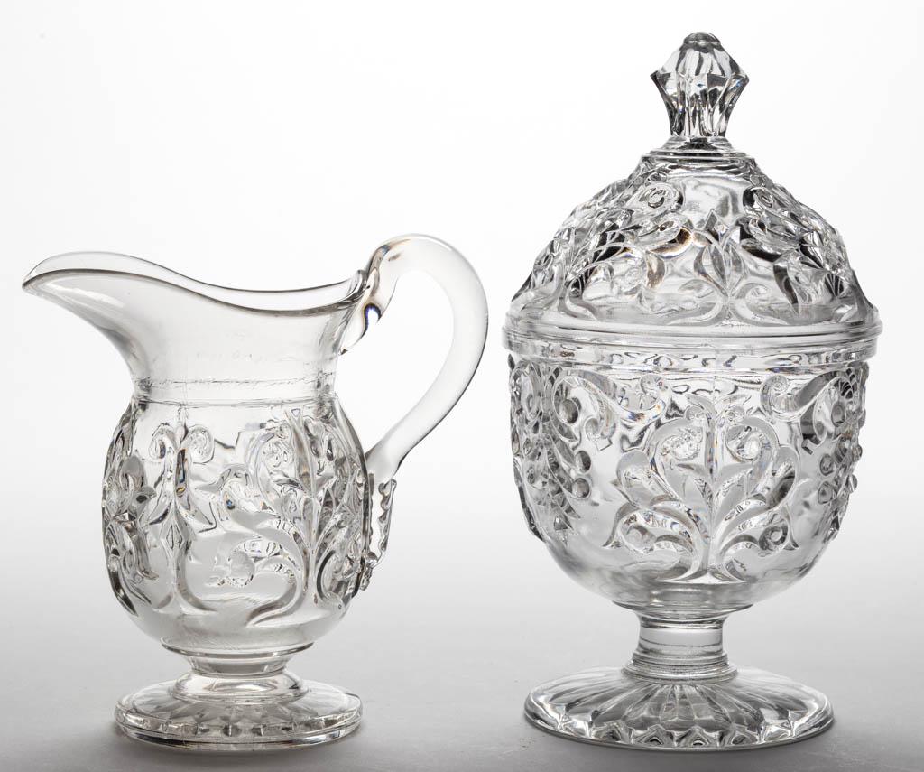 UNLISTED FLINT EAPG COVERED SUGAR AND CREAMER: UNLISTED FLINT EAPG COVERED SUGAR AND CREAMER, colorless lead glass, creamer with applied handle, each raised on a circular foot, creamer with 20 petals to underside, sugar with 19 petals to underside