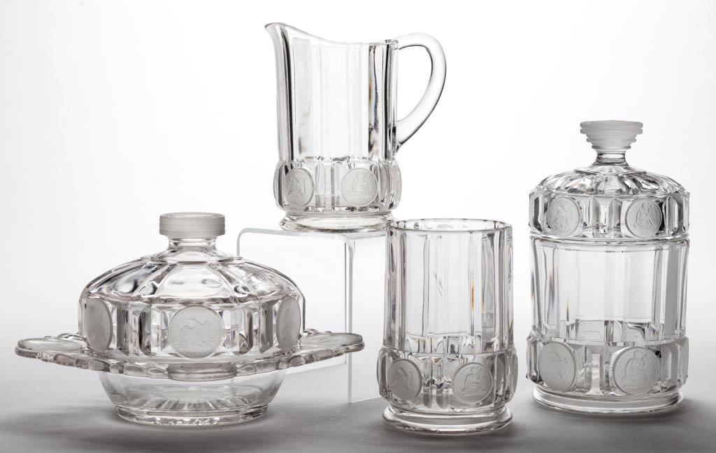 U. S. COIN / SILVER AGE (OMN) FOUR-PIECE TABLE SET: U. S. COIN / SILVER AGE (OMN) FOUR-PIECE TABLE SET, colorless with frosted coins, comprising a covered butter dish, covered sugar bowl, creamer, and spooner. Central Glass Co. 1891-1892.4 5/8" to 6 7/