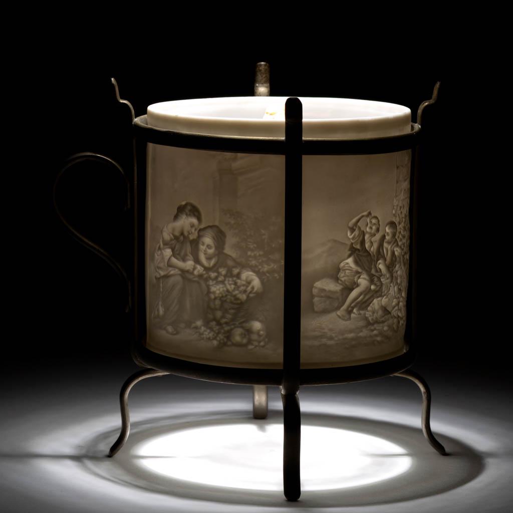 CONTINENTAL PORCELAIN LITHOPHANE HAND LAMP: CONTINENTAL PORCELAIN LITHOPHANE HAND LAMP, cylindrical lithophane featuring four different panels depicting children including the Melon Eaters and Dice Players, mounted in a nickel-plated frame with