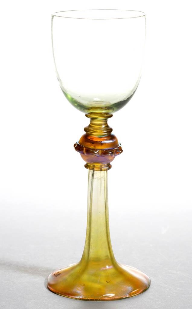 TIFFANY FAVRILE ART GLASS GOBLET: TIFFANY FAVRILE ART GLASS GOBLET, pale green ovoid bowl lacking iridescence, raised on a knop connector with applied rigaree, flaring Panel-Optic stem/base, base having iridescence, signed "L.C.T. M94