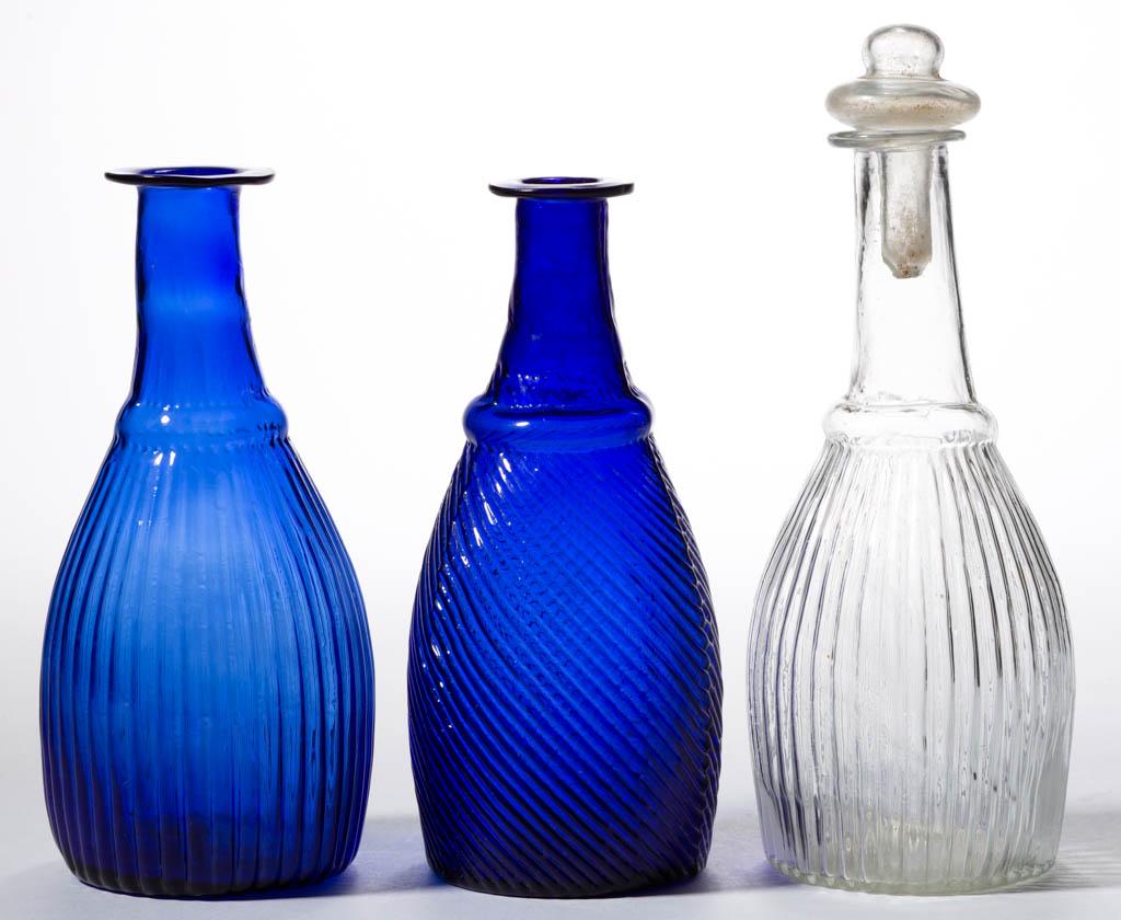 BLOWN-MOLDED THREE MOLD CRUETS / TOILET BOTTLES, LOT OF: BLOWN-MOLDED THREE MOLD CRUETS / TOILET BOTTLES, LOT OF THREE, comprising a cobalt blue GI-3 Type 1 lacking a stopper, a cobalt blue GI-7 Type 3 lacking a stopper, and a colorless GI-7 Type 2 with a c