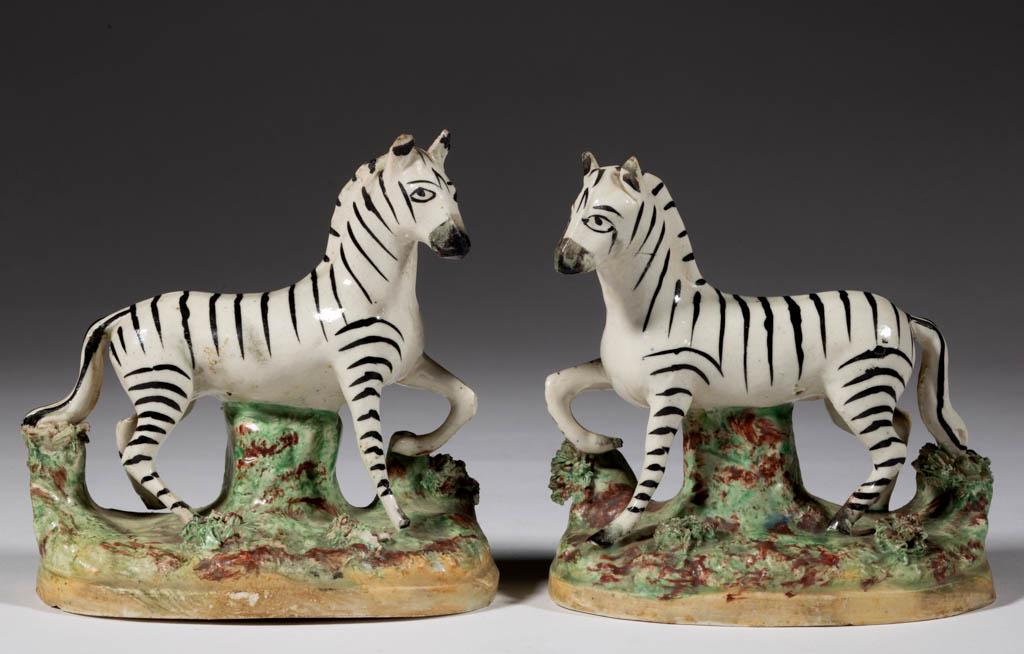 ENGLISH STAFFORDSHIRE ZEBRA CERAMIC PAIR OF FIGURES: ENGLISH STAFFORDSHIRE ZEBRA CERAMIC PAIR OF FIGURES, each standing on oval base with earthy polychrome decoration and shredded clay grass, having black stripes with one front foot raised, decorated in