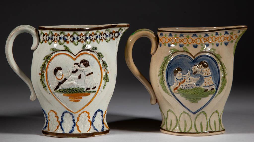 ENGLISH PEARLWARE / PRATTWARE CERAMIC PITCHERS, LOT OF: ENGLISH PEARLWARE / PRATTWARE CERAMIC PITCHERS, LOT OF TWO, each having heart-shaped medallions on both sides with "Mischievous Sport and Sportive Innocence" relief scenes in polychrome decoration, fe