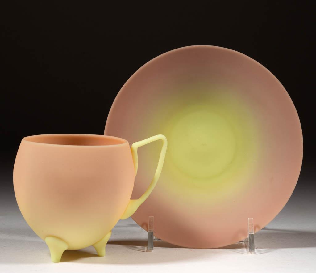 MT. WASHINGTON BURMESE CUP AND SAUCER: MT. WASHINGTON BURMESE CUP AND SAUCER, plush, cup having a fine applied handle and three applied feet, each having a polished pontil mark, saucer retaining a partial "BURMESE" paper label. Mt. Washing