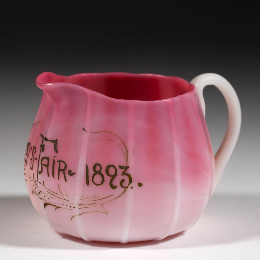 WORLD'S FAIR RIBBED PEACHBLOW CREAMER: WORLD'S FAIR RIBBED PEACHBLOW CREAMER, plush, 12 ribs, "Worldâ€™s Fair / 1893" in gold script, applied handle, rough pontil mark. Probably Libbey Glass Co./New England Glass Co., or Mt. Washingto