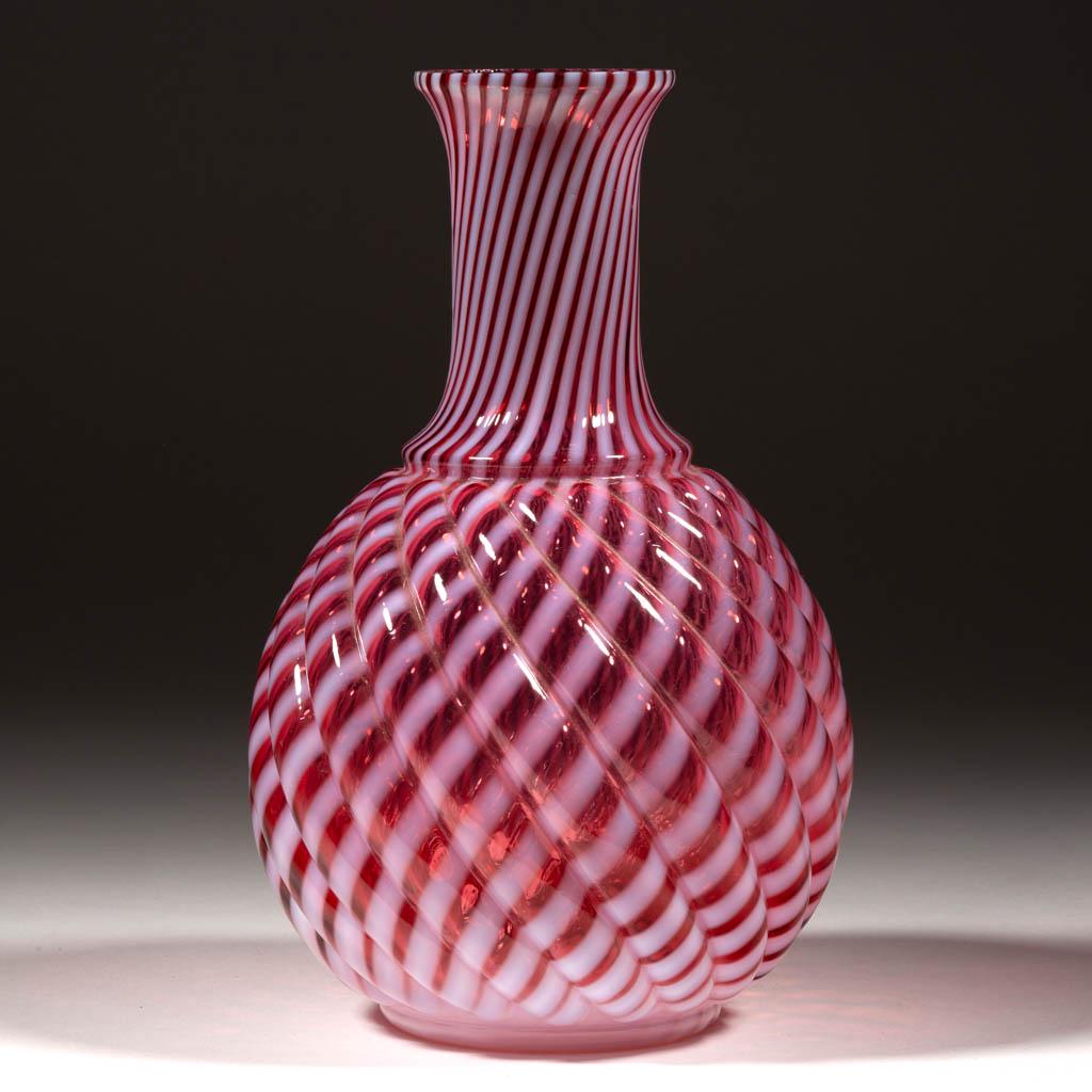 REVERSE SWIRL WATER CARAFE: REVERSE SWIRL WATER CARAFE, cranberry opalescent, factory-polished rim. Maker unverified. 1888-1902. 8 1/4" H.Undamaged.Literature: Parallels Heacock/Elmore - Opalescent Glass From A to Z, p. 96, midd