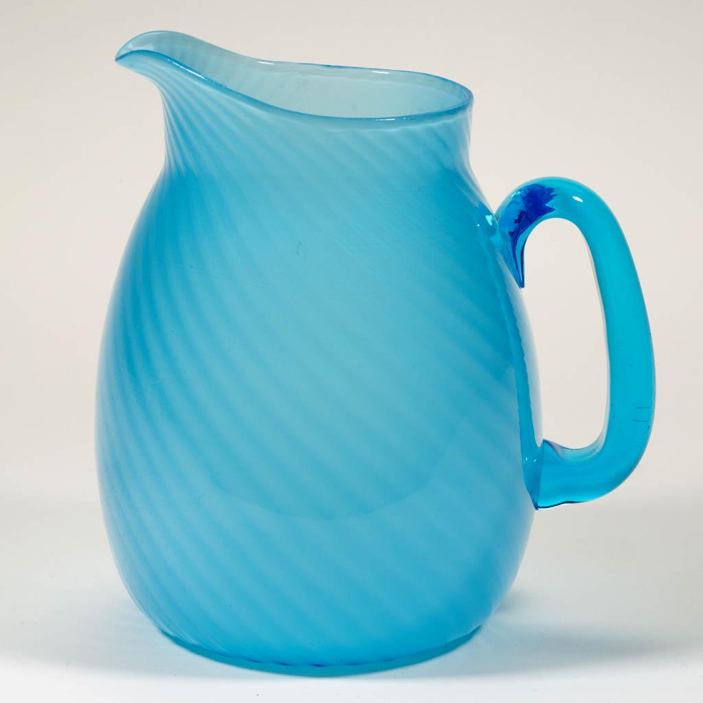 HOBBS NO. 207 / MURANO WATER PITCHER: HOBBS NO. 207 / MURANO WATER PITCHER, Sapphire Alabaster/blue cased, swirled optic ribs, ovoid rim, applied transparent blue handle, polished pontil mark. Hobbs, Brockunier & Co. Circa 1887. 7 3/4" H.