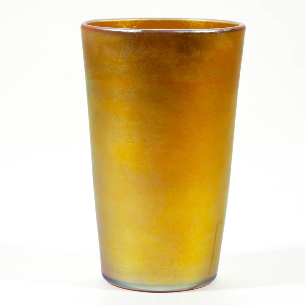 QUEZAL IRIDESCENT ART GLASS TUMBLER: QUEZAL IRIDESCENT ART GLASS TUMBLER, golden iridescent, polished pontil mark, signed "QUEZAL". Quezal Art Glass and Decorating Company. First quarter 20th century. 4 1/2" H.Undamaged. An open bubble t