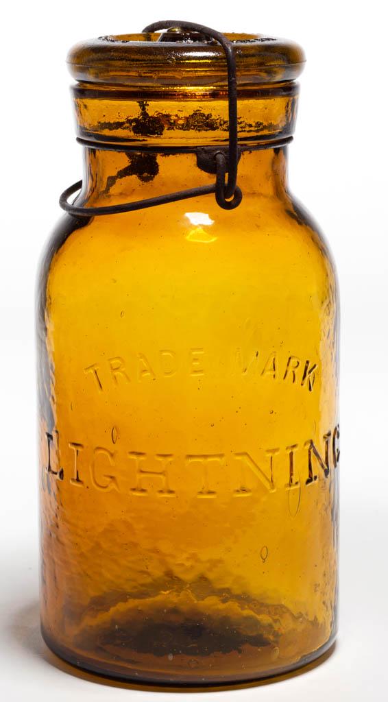 LIGHTNING FRUIT JAR: LIGHTNING FRUIT JAR, bright yellow amber, quart, embossed "TRADE MARK / LIGHTNING" to front, base embossed "PUTNAM / 2", original wire bail and glass lid embossed with three patent dates. Outstanding 