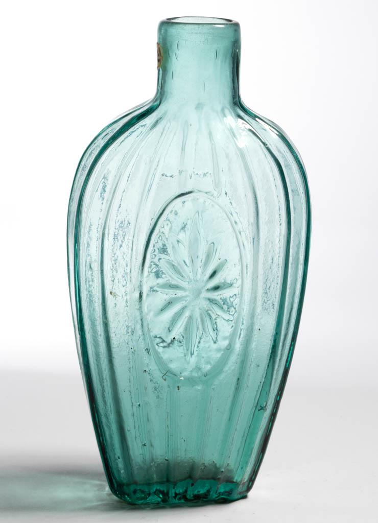 GVIII-29 SUNBURST FLASK: GVIII-29 SUNBURST FLASK, strong blue green, three-quarter-pint, plain mouth, rough pontil mark. United States. 1830-1850. 6 7/8" H.Undamaged with typical high-point wear.Literature: McKearin/Wilson -