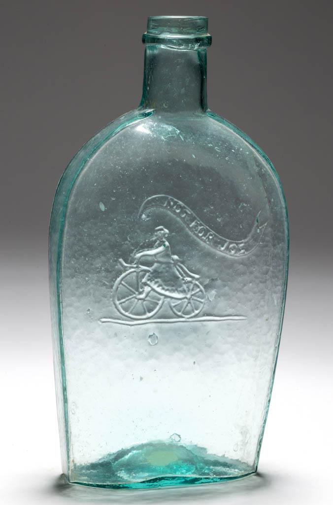 GXIII-2 GIRL ON BIKE - PLAIN PICTORIAL FLASK: GXIII-2 GIRL ON BIKE - PLAIN PICTORIAL FLASK, aquamarine, pint, embossed "NOT FOR JOE" in banner above rider, applied flat collar below the plain mouth, Type 22 base. Nicely whittled surface. 1870-188